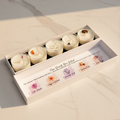 Set of five different small tea lights in a box with labels 